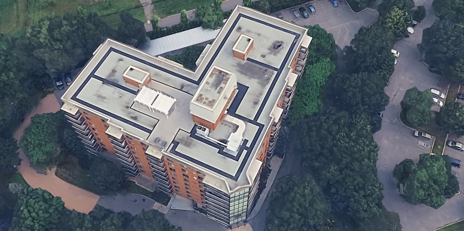 Aerial view of a multi-story residential apartment building roof with rooftop equipment, ahead of a roof condition inspection